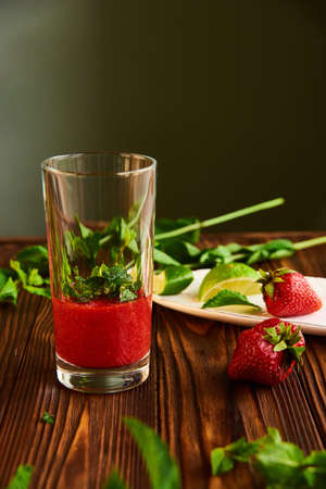 smoothie into a glass. lime, strawberry, mint - ingredients for making lemonade on brown wooden tableの写真素材