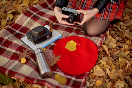 Checkered red and yellow plaid and autumn leaves, book, little silver metal thermos and old retro cameraの写真素材