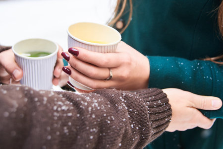 drink hot herbal tea in paper cups for two on street in cold winter weatherの写真素材