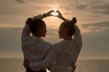 unity and closeness two young women on sea sunrise background. walking to ocean or sea beach in vacation.の写真素材