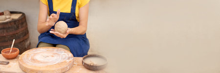 woman hands sculpt from clay. potter in blue apron with wet clay in lump hands.の写真素材