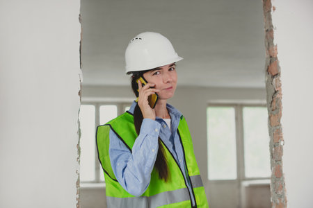 foreman woman consults clients on mobile phone. Inspector or Safety Supervisor in construction site. woman in man construction professionの写真素材