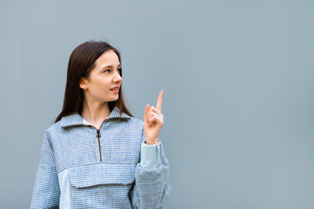 teen girl doing point finger gesture with hand on blue backgroundの写真素材