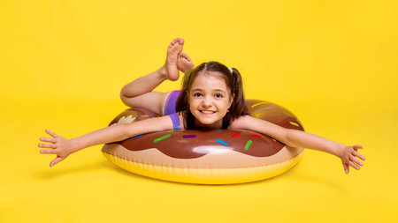 child girl swimming practicing, training with inflatable ring on yellow backgroundの写真素材