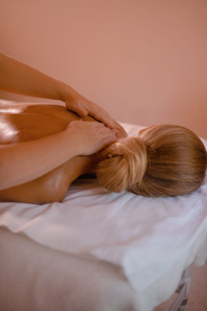 relaxing woman getting massage of neck in beauty salon with copy space on beige background