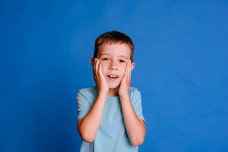 headshot boy afraid to go to doctor, schoolboy in blue mockup T-shirt over light blue studio backgroundの写真素材