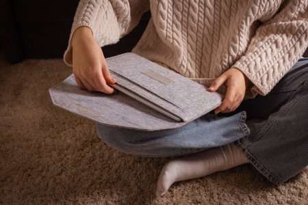 Felt laptop Sleeve protects from scratches, dings and dust. woman open case with laptop sitting on carpet at homeの写真素材