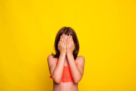 child girl hide face behind hands. See nothing concept. little girl covers her face with hands.の写真素材
