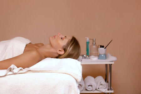 woman client in spa salon lie and ready for massage and spa procedures in beige roomの写真素材