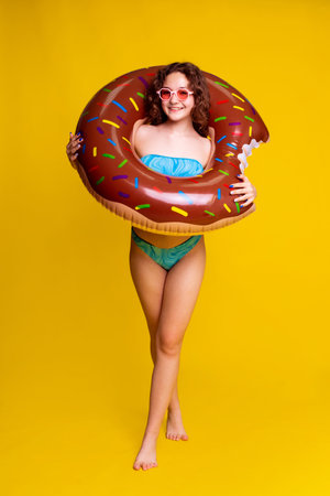 summer beach content with girl holding inflatable ring on yellow background.の写真素材