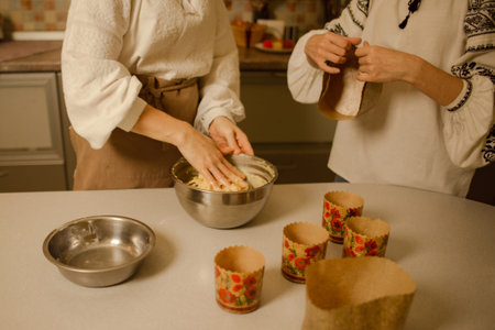 preparing for celebration of Orthodox Easter, woman with sister kneads dough for traditional paska,