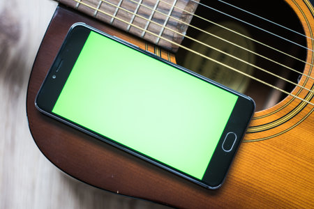 Smartphone with green screen on an acoustic guitar