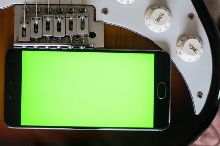 Smartphone with green screen on an Electric Guitars guitar