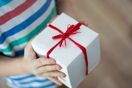 Box with a gift in the hands of a childの写真素材