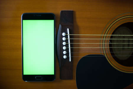 Smartphone with green screen on an acoustic guitarの写真素材