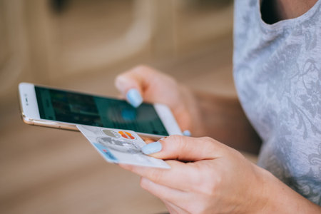 Woman holding a credit card and using cell phone for online shopping.