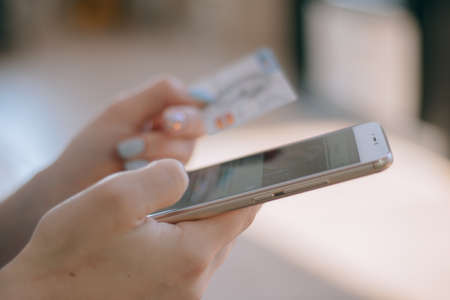 Woman holding a credit card and using cell phone for online shopping.の写真素材