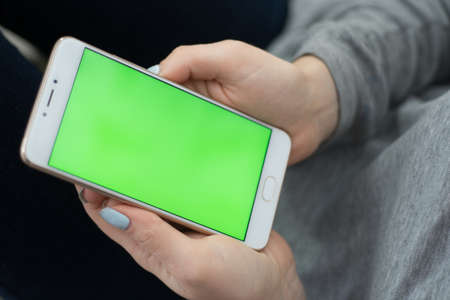 Beautiful girl holding a smartphone in the hands of a green screen green screen, hand of man holding mobile smart phone with chroma key green screen on white background, new technology conceptの写真素材