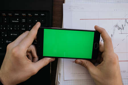 Side view of a man with a marker and stable standing against a concrete wall with graphs drawn on it. Concept of statistics and stocks With the green screen keying for smartphoneの写真素材