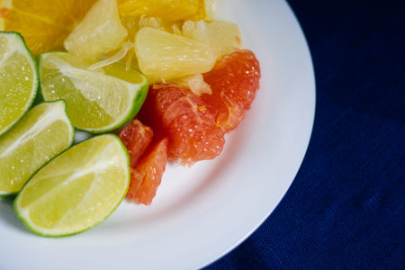 stack of citrus fruits slices. Oranges and lemons limes, grapefruit, pomelo. on a white plate
