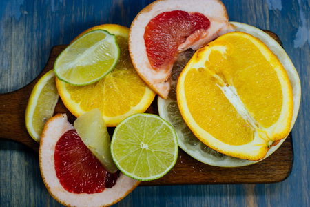 Various citrus fruit cut into slices orange, lemon, lime, grapefruit, pomelo. Spread out on a wooden board on a vintage background of natural wood texturing.の写真素材