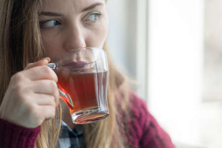 portrait of a beautiful young woman, cute girl arrived on a moped in a coffee shop to drink cup of tea.の写真素材