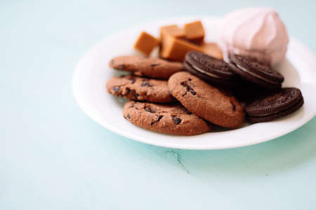 Plate of cookies with chocolate fudge and marshmallow on a background of mint-colored wooden textureの写真素材