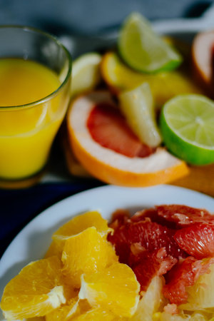 Various citrus fruit cut into slices orange, lemon, lime, grapefruit, pomelo and a glass of orange...
