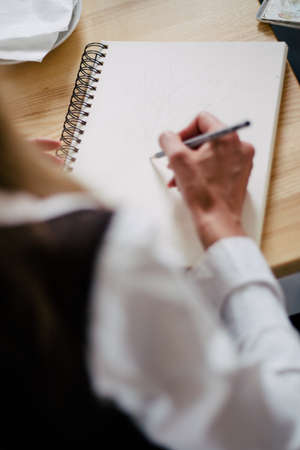 Unrecognizable business person analyzing graphs and taking notesの写真素材