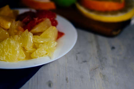 Various citrus fruit cut into slices orange, lemon, lime, grapefruit, pomelo. Spread out on a wooden board on a vintage background of natural wood texturing.の写真素材