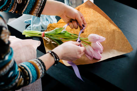 Smiling lovely young woman florist arranging plants in flower shopの写真素材