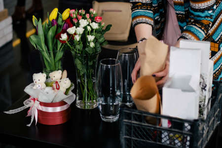 Closeup of hands of young woman florist creating bouquet of pink roses on the tableの写真素材