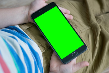 Mock up The child is holding a Smartphone in his hand with a green screen for keying Close-up...