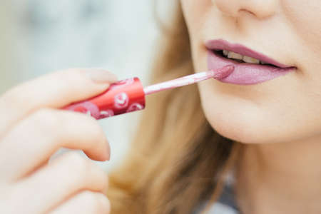 beautiful girl lips close-up, make-up artist applies lipstick brush for make-up, full lips, a woman in a beauty salon. Girl paints her lips red lipstick, make-up artist doing make-up client in a salonの写真素材