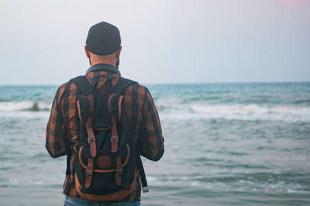 A hipster traveler with a backpack is standing by the sea, travel conceptsの写真素材