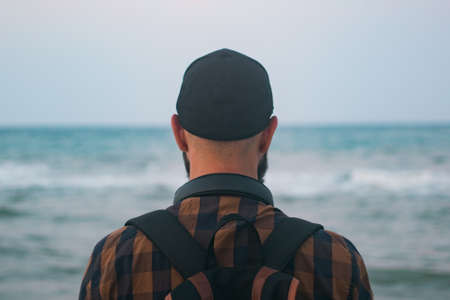 A hipster traveler with a backpack is standing by the sea, travel conceptsの写真素材