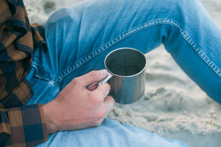 Young man with his morning cup of coffee looking to the ocean viewの写真素材