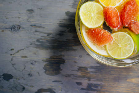 Citrus in water with bubbles in transparent plate Oranges, lemons, greyfrut, Pamela lemonade Space for signature on wood textureの写真素材