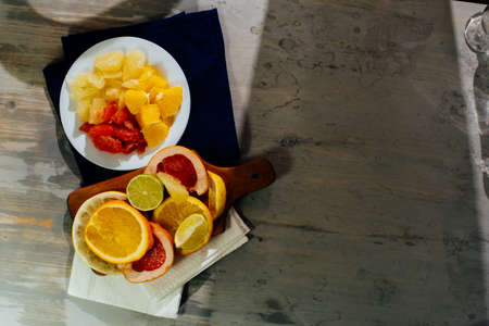 Various citrus fruit cut into slices orange, lemon, lime, grapefruit, pomelo. Spread out on a wooden board on a vintage background of naturalの写真素材