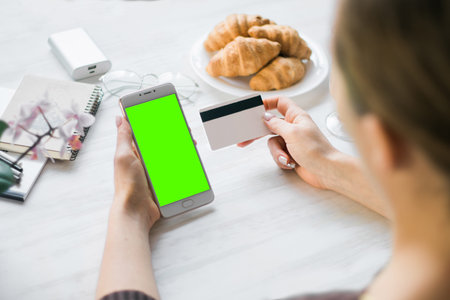 Woman holding a credit card and using cell phone for online shopping.