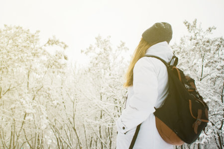 Handsome traveling woman enjoying wilderness in front of incredible mountain lake. Wearing hat,...