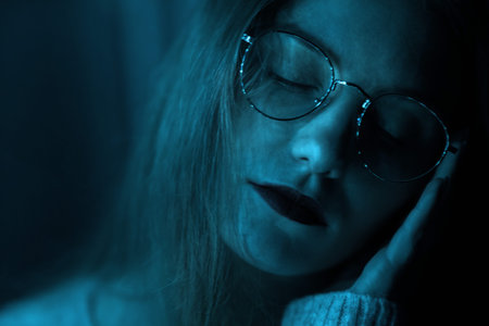 Portrait of a fashionable beautiful girl with glasses in the dark and bokeh. Effect of the focus of...