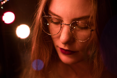 Portrait of a fashionable beautiful girl with glasses in the dark and bokeh. Effect of the focus of...