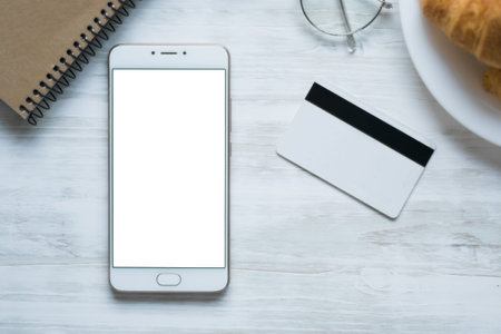 Woman holding a credit card and using cell phone for online shopping.