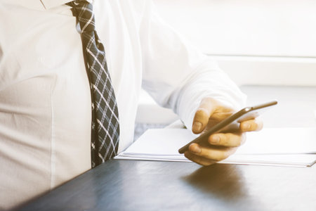 Businessman working with generic design notebook. Holding smartphone in hands. Horizontal, sunlight...