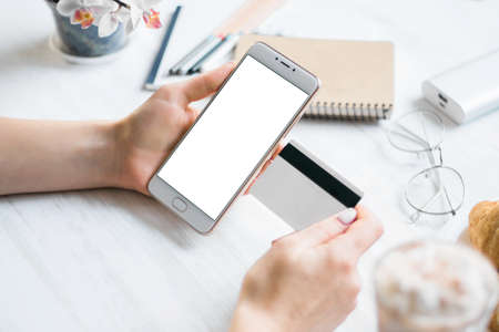 Woman holding a credit card and using cell phone for online shopping.の写真素材
