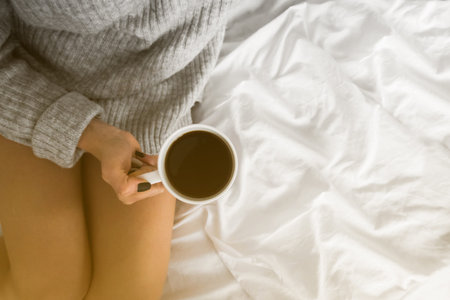 Beautiful woman enjoying morning coffee in bedの写真素材