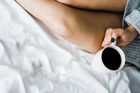 Girl with coffee the morning on the background of the bedの写真素材