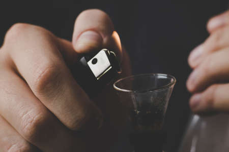 Concepts of medical marijuana use and legalization of the cannabis .A man smokes cannabis weed, a bong and a lighter in his hands. Smoke on a black background. On a black backgroundの写真素材
