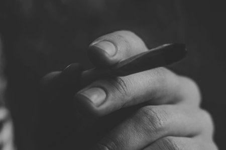 A man smokes cannabis weed, a joint and a lighter in his hands. Smoke on a black background....